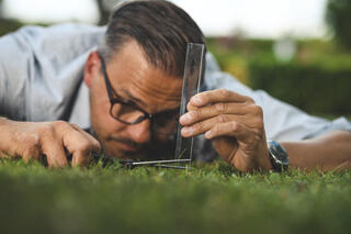 Mann som klipper gress med linjal